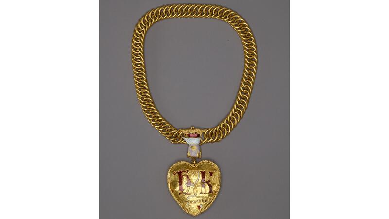 Le dos du pendentif porte les initiales « H » et « K » en majuscules lombardes émaillées rouges. Le British Museum a déclaré que la main émaillée sortant du nuage d'or 24 carats était un motif courant au XVIe siècle, représentant la main de Dieu. (© Les administrateurs du British Museum) Pendentif Coeur Tudor au dos