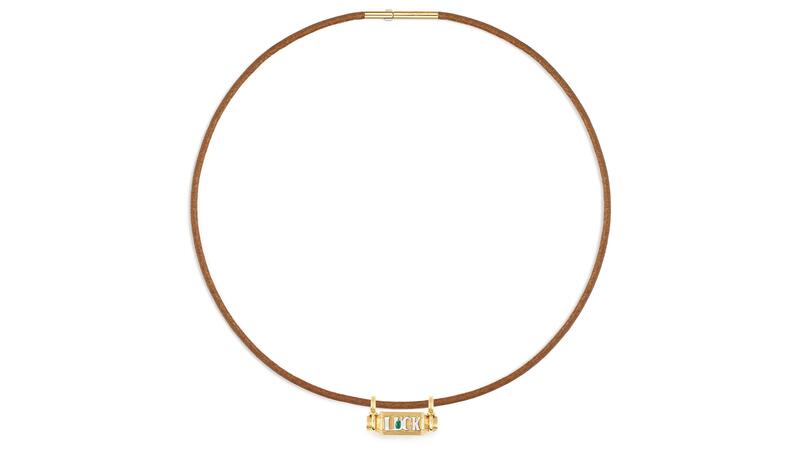 Le médaillon smash « Luck » en or jaune 18 carats indique « LUCK » en or blanc 18 carats accentué par une émeraude de 0,04 carat (6 900 $). Collier médaillon porte-bonheur Marie Lichtenberg