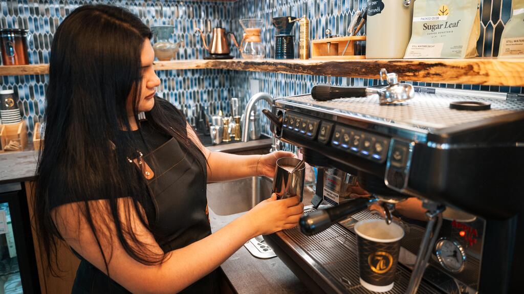 Anisa Garcia, barista à temps plein du 7Cs Cafe, prépare un verre. Le café sert du café provenant de torréfacteurs locaux. Anisa García 7Cs café